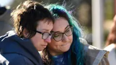 Two people grieve at the scene