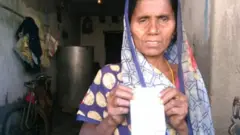 சிறுமியின் ஆதார் அட்டையை காட்டும் தாய் நிஷா தேவி