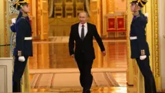 O presidente russo Vladimir Putin entra em salão no Kremlim, no meio de dois guardas