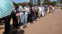Abantu ku miringo bategereje imodoka mu mujyi wa Kigali