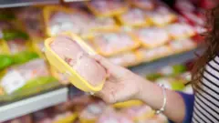 mulher segurando cartela com filés de frango