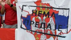 Serbia fans hold up a fllag depicting the outline of Kosovo filled with Serbia's flag, with words translated as 'no surrender'