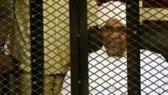 عمر البشیر د محاکمې پر مهال په یوه پنجره کې ناست و