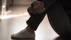Imagem de pessoa sentada no chão abraçando as pernas