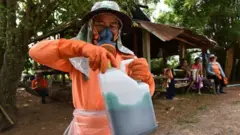 เกษตรกรถือขวดสารเคมี