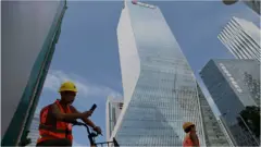 Workers walk in front of the Evergrande headquarters in Shenzhen, southeastern China on September 26, 2021.