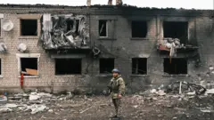A Ukrainian police officer inspects a damaged building in Vovchansk