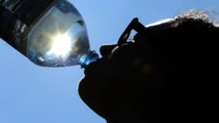 A person drinking from a water bottle with sun shining through the bottle