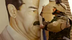 Saddam Hussein poster torn down by US soldier