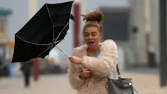 A woman's umbrella turns inside-out in strong winds