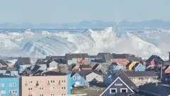 Casas de colores en primer plano y un bloque de hielo enorme al fondo.