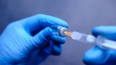 টিকার ভায়াল থেকে টিকা নেয়া হচ্ছে সিরিঞ্জে