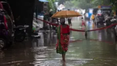 சென்னையில் மழை நீரின் நடுவே நடந்து செல்லும் மூதாட்டி