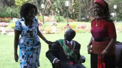 Robert Mugabe (wicaye) umukobwa we Bona(ibumoso) n'umugore we Grace(iburyo)