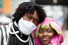 A man and a woman dressed in bright clothes and wigs.