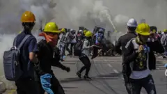 Demonstrators react as tear gas is fired by police during a protest against the military coup in Yangon, Myanmar, 06 March 2021