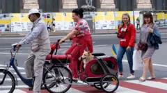 Жінка на велосипеді везе собаку