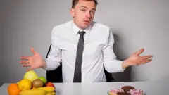 Hombre eligiendo entre frutas bollería.