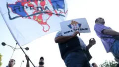 Muškarac drži transparent na kome piše "Nema predaje"