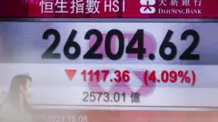 People walk past an electronic display showing the Hang Seng Index in the Central district of Hong Kong on July 26, 2021,