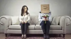 Divanda oturmuş qadın və kişi