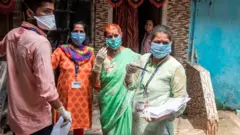 মুম্বাইয়ের সান্টাক্রুজ এলাকায় স্বাস্থ্যকর্মীদের একটি দল কোভিড-১৯ সংক্রমণের লক্ষণ পরীক্ষা করছেন
