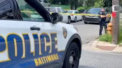 A police officer secures crime scene tape to a pole after a mass shooting at the scene of a Fourth of July holiday weekend block party in Baltimore, Maryland, U.S. July 2, 2023.