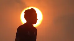 "La silueta de Santiago que se recorta sobre el sol del atardecer en la playa de Bocagrande en Cartagena". Foto de Ricardo Roa.