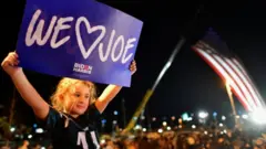 A girl holds a 'We love Joe' sign ahead of Joe Biden's address