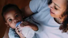 A woman with her baby having a bottle