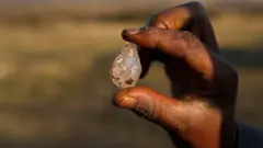 A boy holds what he believes to be a diamond after the discovery of unidentified stones at KwaHlathi village near Ladysmith, South Africa