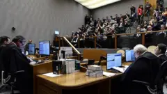 Quinta Turma reunida em julgamento no primeiro plano, e plateia em segundo plano
