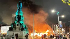 A bus and car on fire on O'Connell Street in Dublin city centre after violent scenes