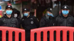 Policías vigilan el mercado de marisco de Huanan, en Wuhan, China.