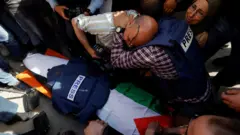 Journalists react next to the body of Al Jazeera correspondent Shireen Abu Aqleh, who was shot dead during an Israeli raid in the occupied West Bank city of Jenin (11 May 2022)