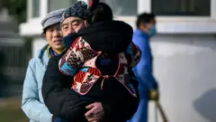 Một người đàn ông ôm con ra khỏi Trung tâm Y tế Vũ Hãn.