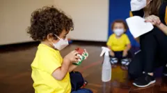 criança de máscara brinca em escola