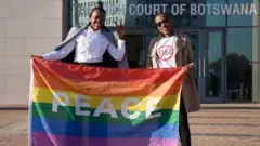 Activists pose with a rainbow flag as they celebrate outside Botswana High Court in Gaborone after the landmark ruling in June