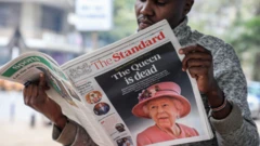 A newspaper vendor seen reading a local daily reporting on the death of Queen Elizabeth II in the city of Nairobi. Queen Elizabeth II