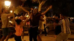 Abashyigikiye Perezida wa Tunisia Kais Saied bishima i Tunis, nyuma yuko inteko ishingamategeko ihagaritswe, ku itariki ya 26 y'ukwezi kw karindwi mu 2021