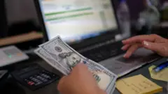 A small businesswoman in Venezuela counts US dollar notes