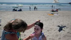 A woman helps her daughter with sunscreen