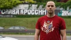 達米揚·克內澤維奇在貝爾格萊德街頭一塊用俄語寫著"榮光歸俄羅斯"的標語前。