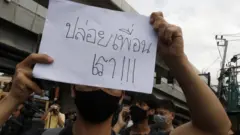 Pro-democracy protester holds a placard with a message "Free our friends" as they gather for an anti-government protest at Kaset Intersection in Bangkok,