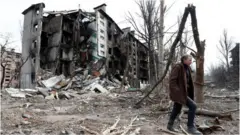 Man walks near residential building in Mariupol