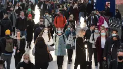Pessoas caminham em estação de trem