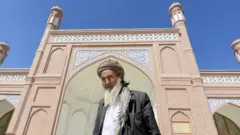A man standing outside Eid Gah mosque