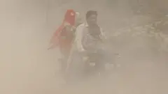 zagadjen vazduh nju delhi indija ljudi na motoru