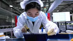 A woman works on the production line of solar panels at a factory in Sihong county in east China's Jiangsu province on 23 January 2025