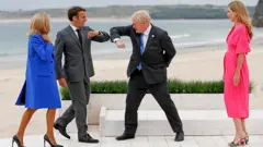Prime Minister Boris Johnson greet France's President Emmanuel Macron with an elbow bump as their spouses look on in Cornwall, during the G7 summit